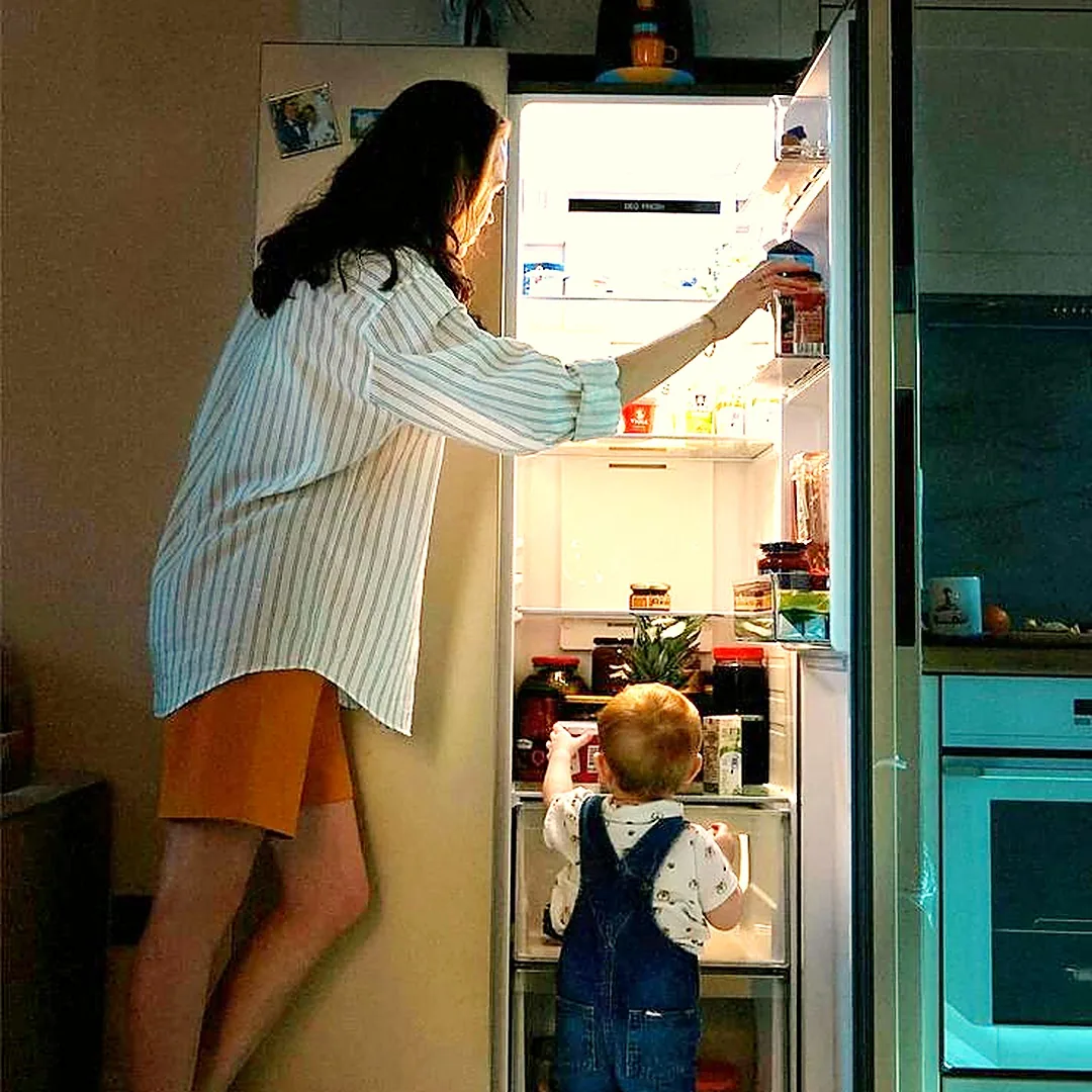 IMAGEN: mum and young child at the fridge in an Australian home, pointing together at a visual morning routine strip with picture cards